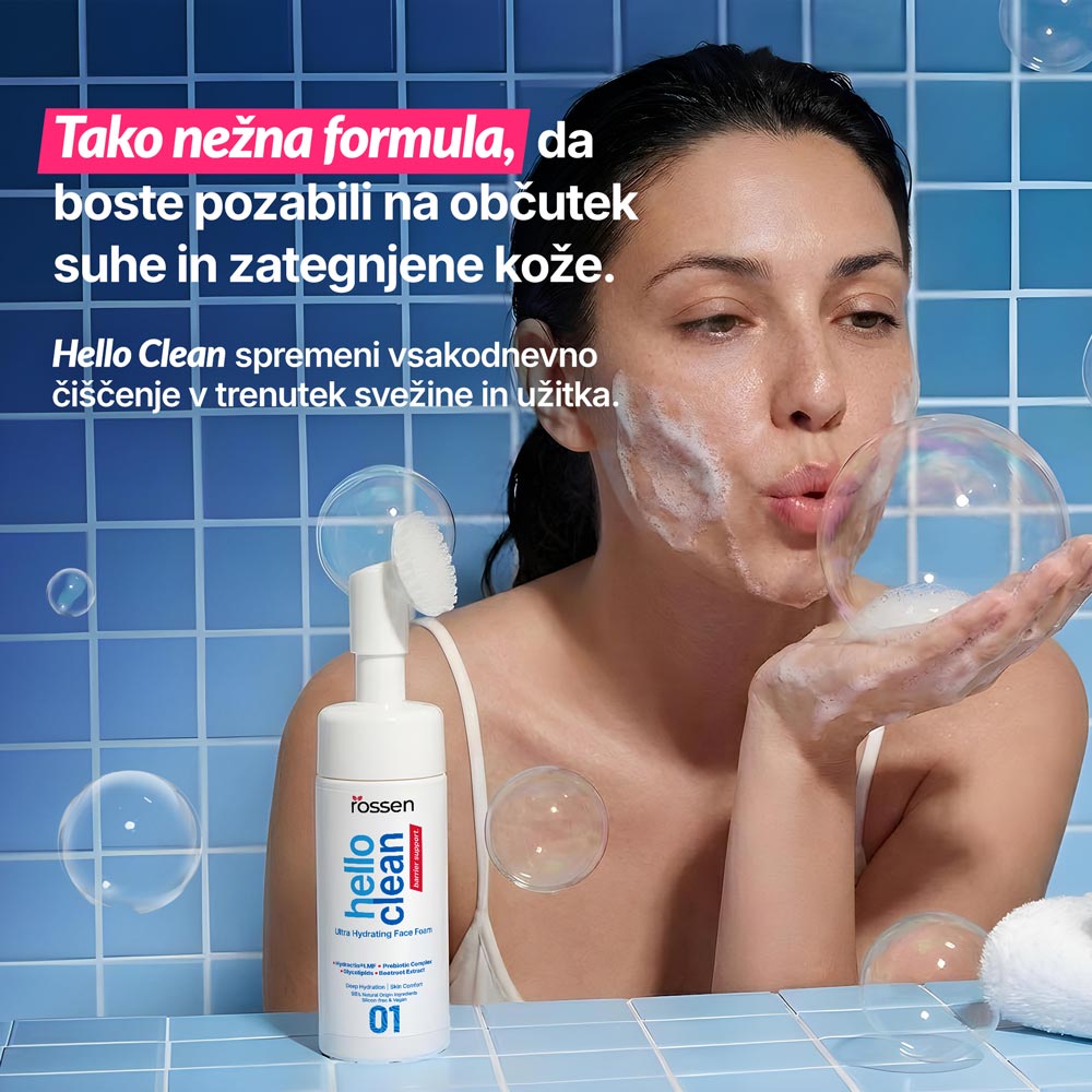 Woman with foamy face blowing bubbles in a blue-tiled bathroom; bottle of Hello Clean Ultra Hydrating Face Foam on the counter; pink banner text touting a gentle formula in Slovenian.