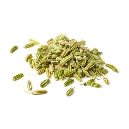 Pile of greenish fennel seeds scattered on a white background, close-up view for cooking use