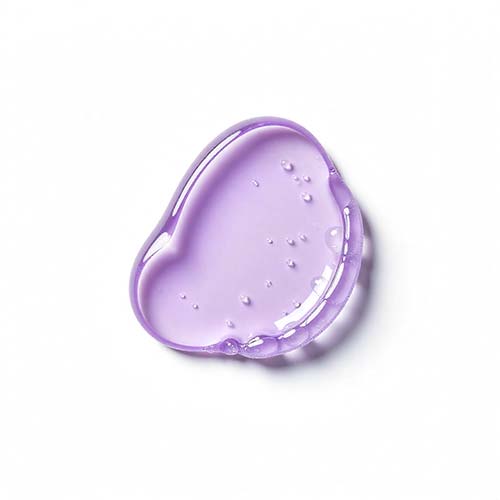 Purple heart-shaped gel droplet on a white background, glossy and translucent with a few tiny bubbles in it.